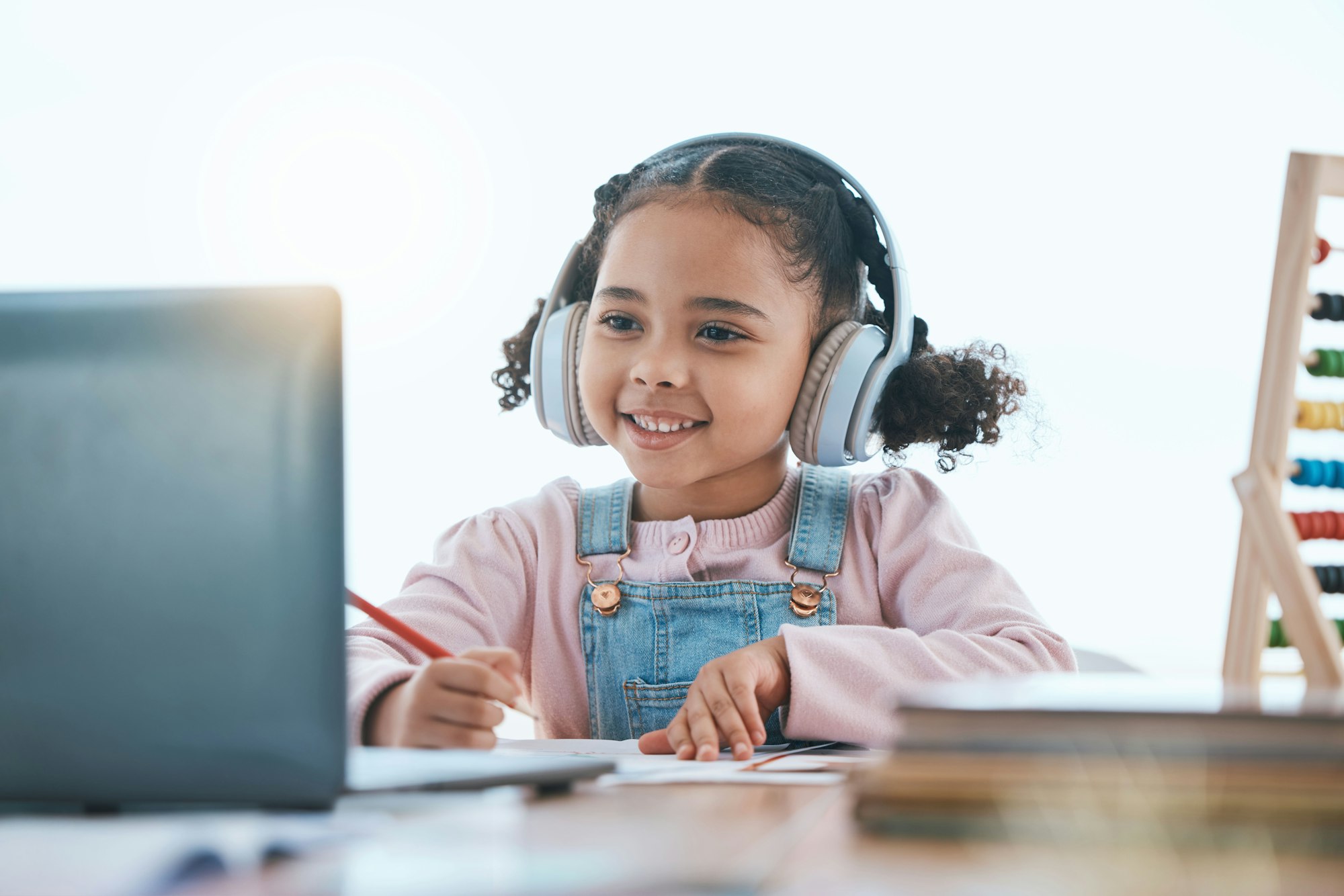 Online education, laptop and headphones of child in e learning, language translation and writing in