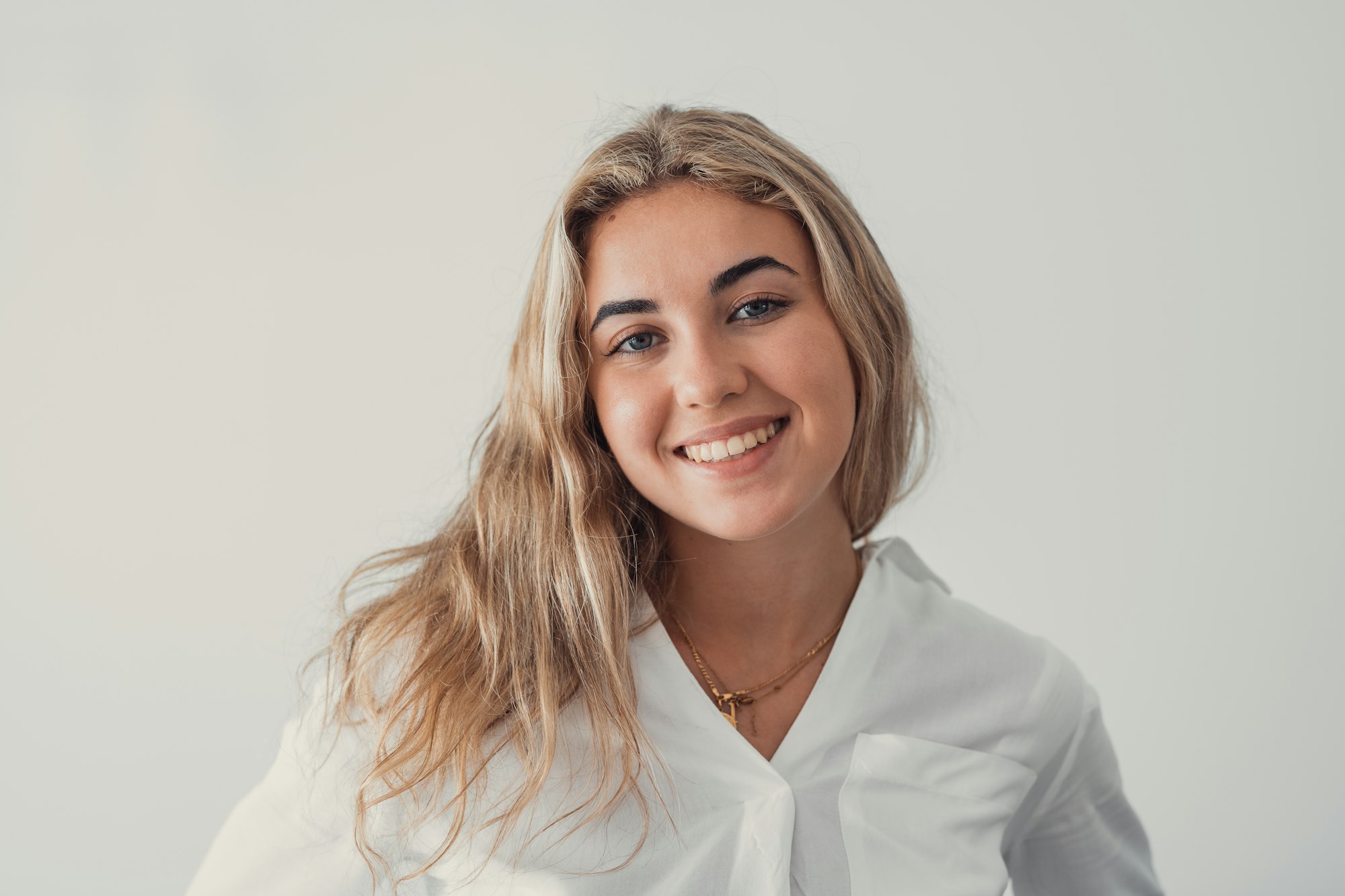 Close up overjoyed woman laughing, sitting on couch at home, head shot portrait